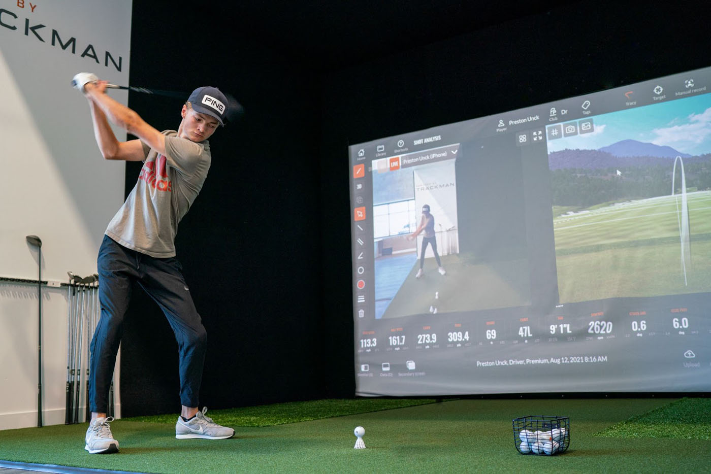 A golfer at Tee Box practicing their swing with the advanced Trackman simulator technology.