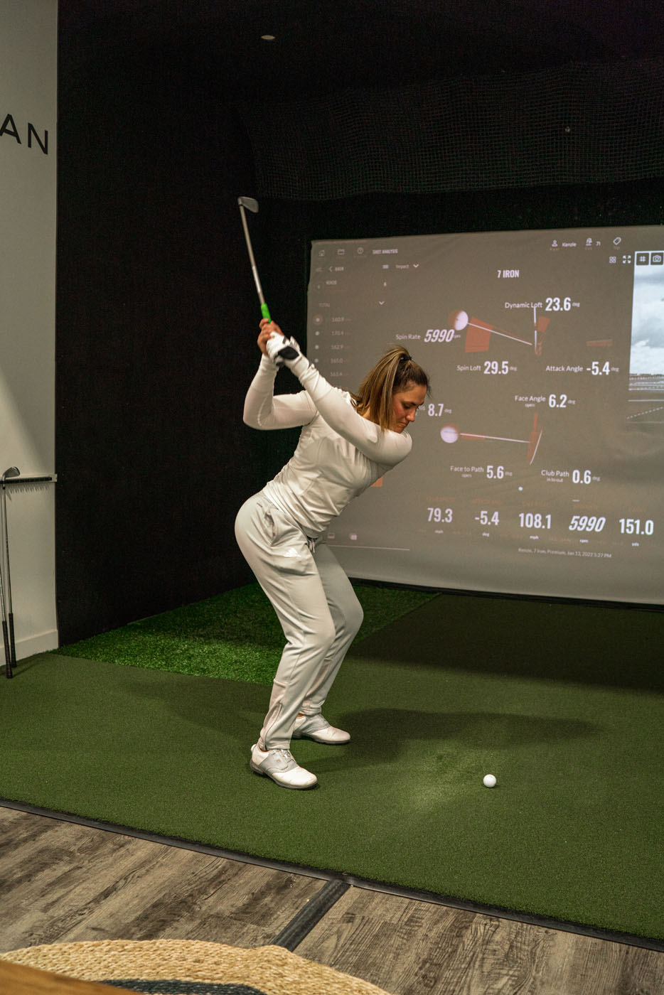 An image of a girl using our indoor golf practice systems to refine her swing.