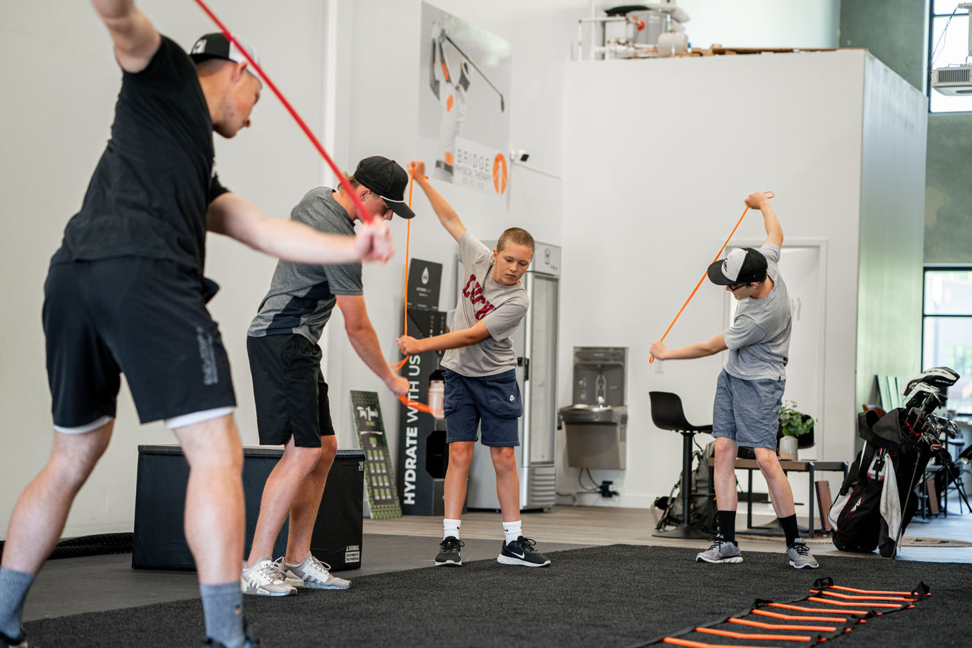 An image of a golf teacher at Tee Box helping young golfers build the phsycial skills to optimize their game.